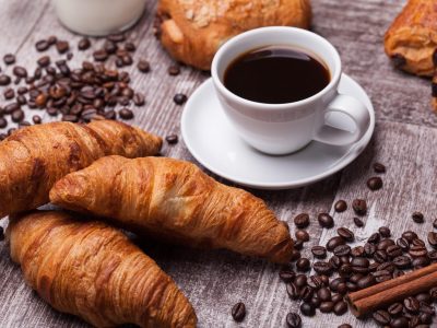 Coffee and croissant for breakfast on rustic wooden table