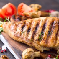 Grilled chicken fillets on wooden board on Gray concrete background. Healthy diet food concept