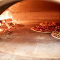 pizza baking in oven at pizzeria