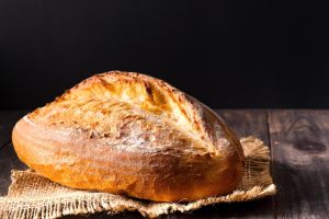 Rustic bread roll or french baguette, wheat and flour on wooden. Rural kitchen or bakery -